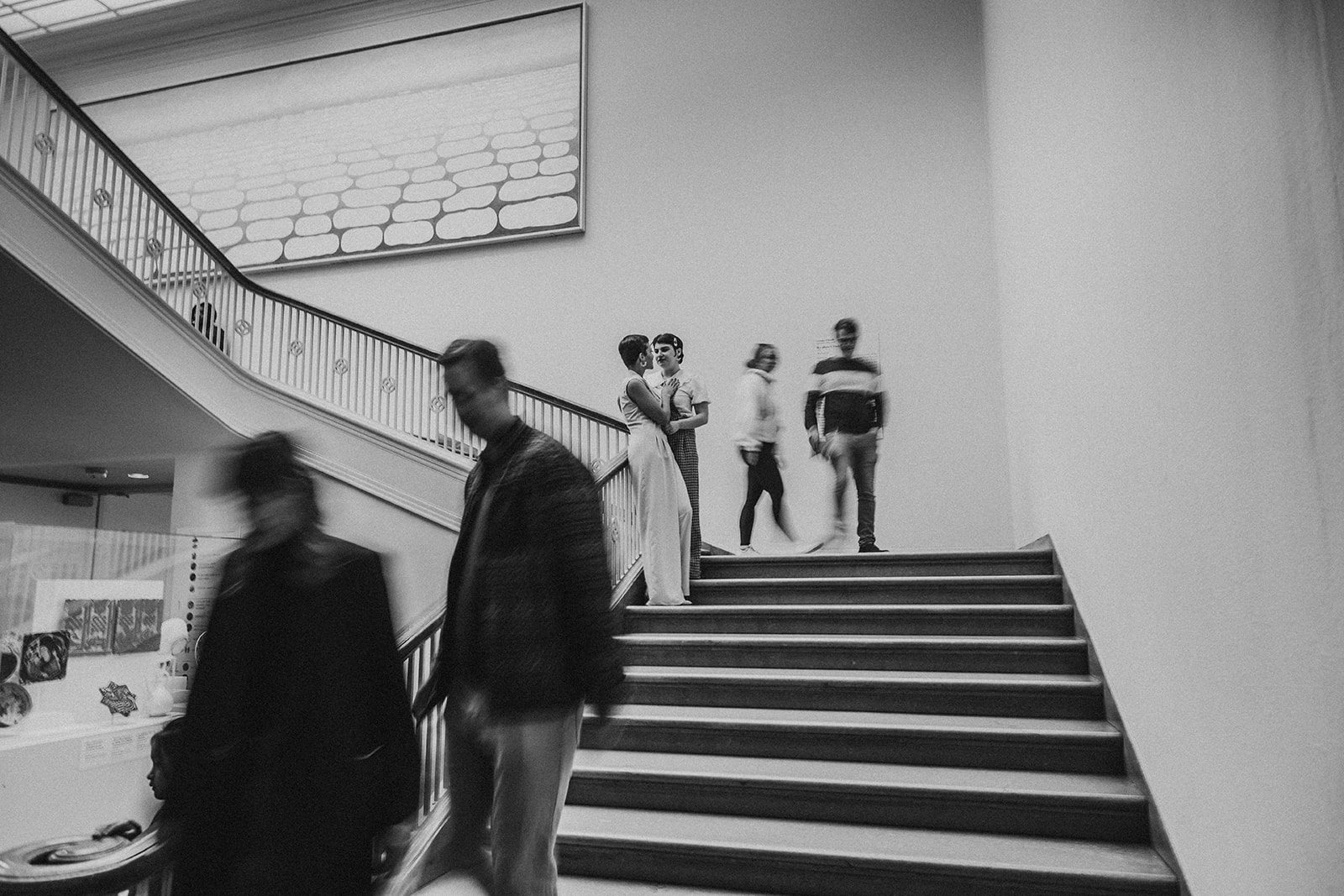 A slowed down shot of the couple standing on the staircase, people cross by them and blurr in the photograph. This shot is turned Black and white.